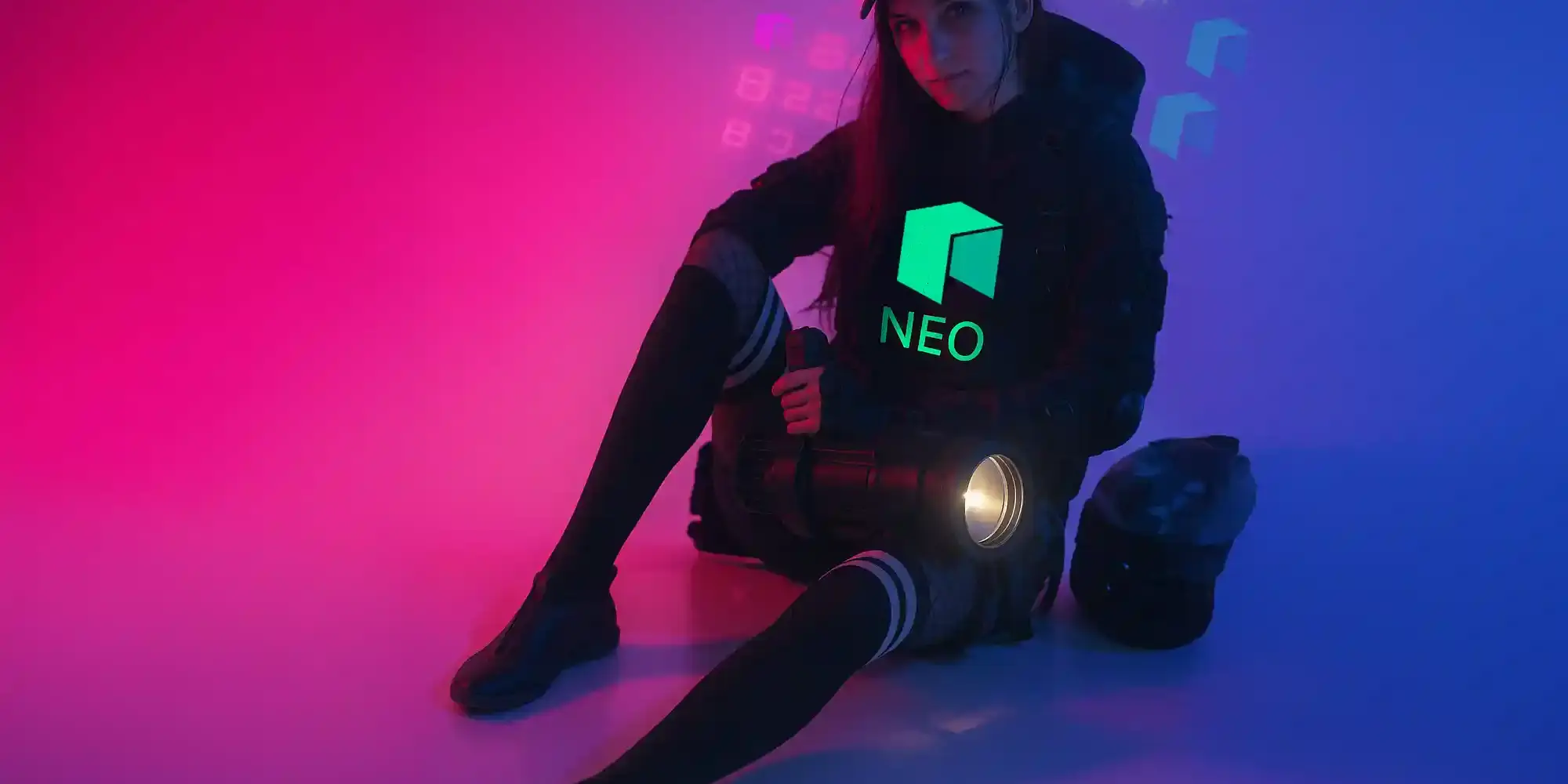 Woman in cyberpunk outfit sitting in neon-lit room, wearing a black hoodie with glowing green NEO logo – crypto streetwear aesthetic
