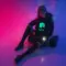 Woman in cyberpunk outfit sitting in neon-lit room, wearing a black hoodie with glowing green NEO logo – crypto streetwear aesthetic